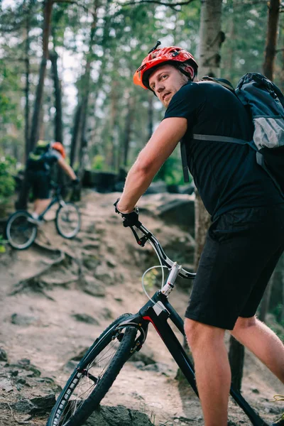 Jovens motociclistas julgamento ativo montando subida na bela floresta de pinheiros — Fotografia de Stock