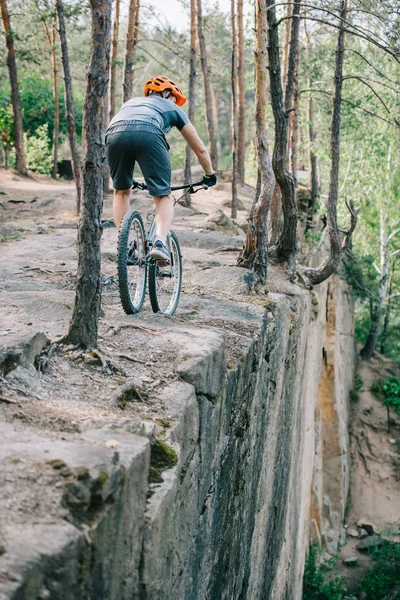 Extreme trial biker riding on cliff at forest — Stock Photo