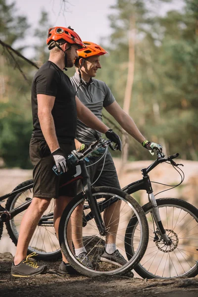 Felizes jovens motociclistas julgamento de pé no penhasco com bicicletas — Fotografia de Stock