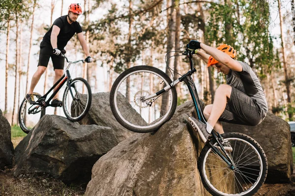 Athletic young trial bikers riding on rocks outdoors — Stock Photo