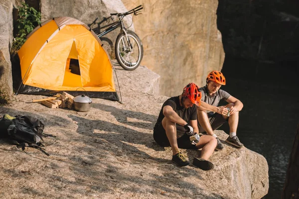 Young bike travellers with canned food sitting on cliff — Stock Photo