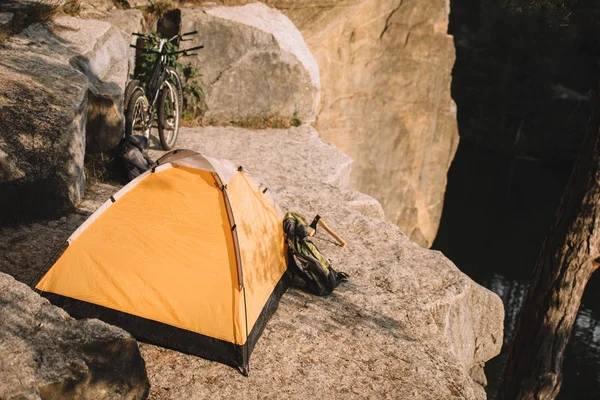 Палатка для кемпинга с пробными велосипедами и рюкзаком на скалистом утесе — стоковое фото