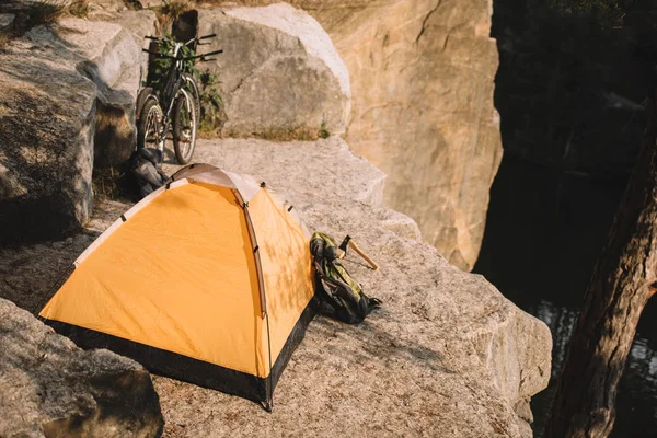 Barraca de acampamento com bicicletas experimentais e mochila em belo penhasco rochoso — Fotografia de Stock