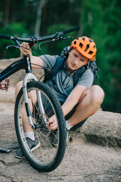 Handsome young trial biker attaching wheel to bicycle outdoors — Stock Photo