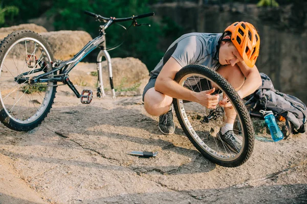 Giovane prova motociclista fissaggio ruota bici all'aperto — Foto stock