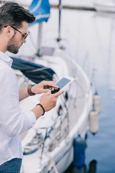 Cropped shot of young man in sunglasses using digital tablet at yacht — Stock Photo