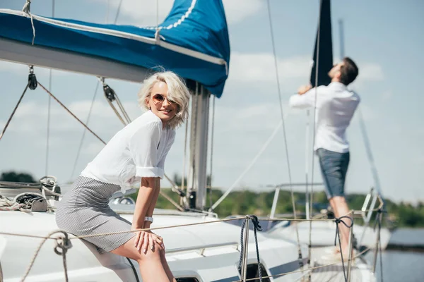 Schöne junge Frau mit Sonnenbrille lächelt auf Jacht in die Kamera — Stockfoto