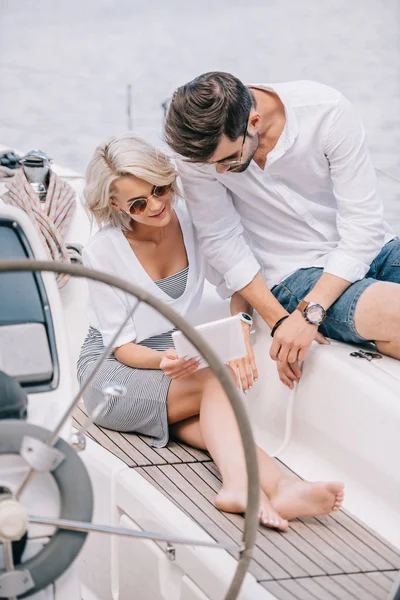 Stylish young couple in sunglasses using digital tablet on yacht — Stock Photo