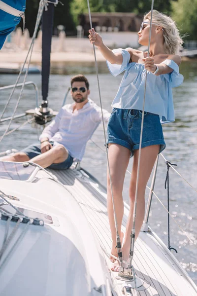 Young man in sunglasses sitting and looking at beautiful girl on yacht — Stock Photo