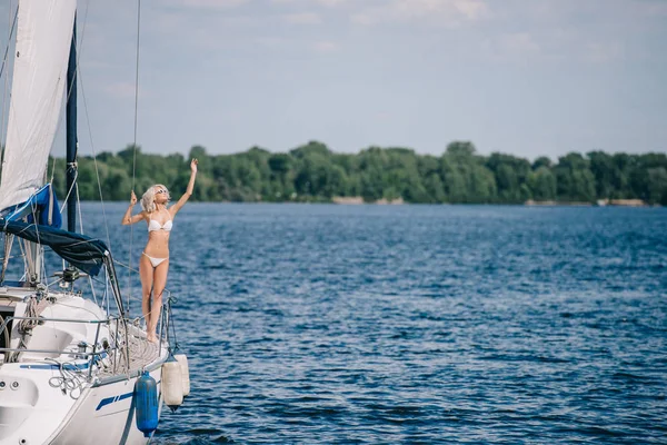 Beautiful blonde woman in bikini standing on yacht — Stock Photo