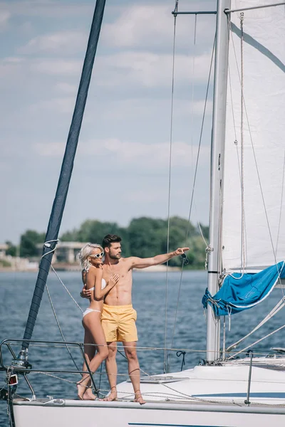 Hermosa pareja joven mirando hacia otro lado mientras están de pie juntos en el yate - foto de stock