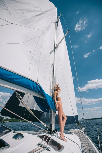 Вид сбоку привлекательной молодой женщины в купальниках, стоящей на яхте — стоковое фото