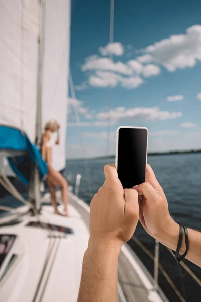 Image recadrée de l'homme prenant en photo de petite amie sur smartphone sur yacht — Photo de stock