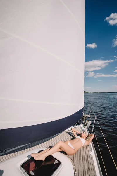 Attractive young woman in swimwear relaxing and having sunbath on yacht — Stock Photo