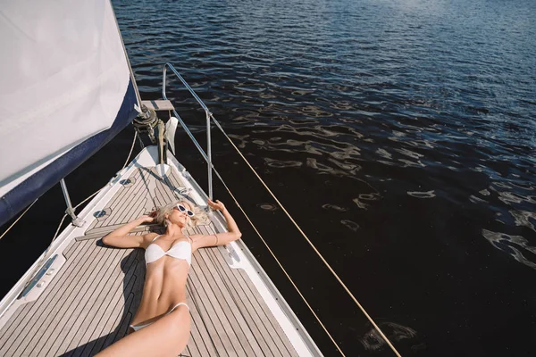 Vue grand angle de jeune femme séduisante en maillot de bain ayant bain de soleil sur yacht — Photo de stock