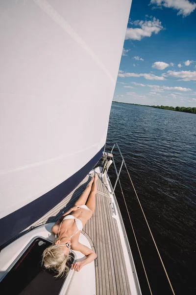 Vista elevada de la mujer joven en bikini relajante y tomando el sol en el yate - foto de stock