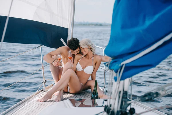 Jeune couple en maillot de bain relaxant avec verres à champagne sur yacht — Photo de stock