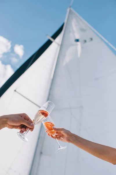 Immagine ritagliata di fidanzato e fidanzata clinking da occhiali con champagne su yacht — Foto stock