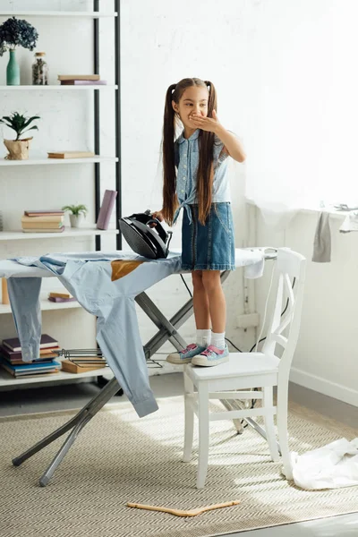 Pre-adolescent child burning shirt with iron at home — Stock Photo