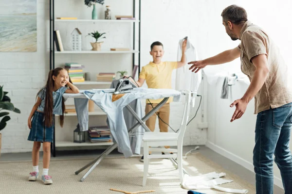 Bambini disobbedienti che bruciano vestiti con ferro a casa, concetto di genitorialità — Foto stock