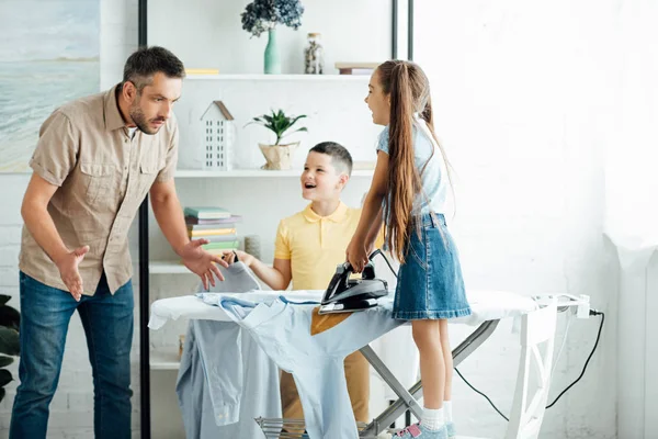 Surprised father looking at burned shirt after ironing at home — Stock Photo