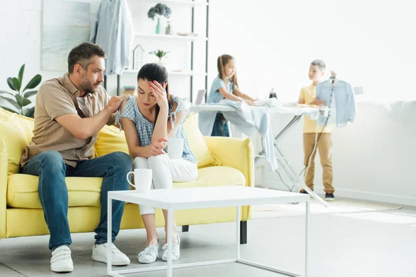 Kinder bügeln Kleidung, Mutter hat Kopfschmerzen zu Hause — Stockfoto