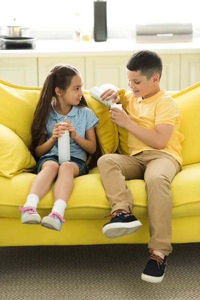 Sorella e fratello mangiare crema sul divano a casa — Foto stock