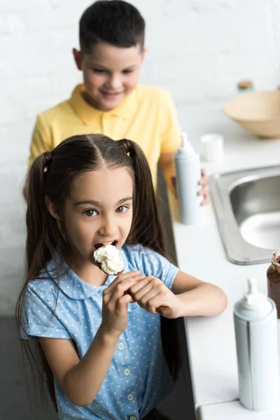 Vista ad alto angolo di sorella e fratello mangiare dolci in cucina a casa — Foto stock