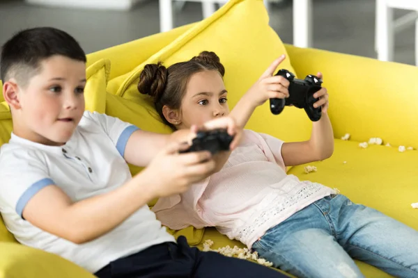 Hermana seria y hermano jugando videojuego en casa - foto de stock