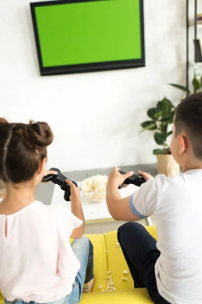 Back view of sister and brother playing video game at home — Stock Photo
