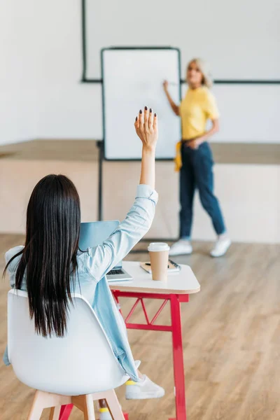 Rear view of student raising hand to answer at question of teacher — Stock Photo