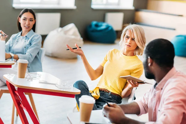 Verwirrte junge Studenten sitzen zusammen an der Hochschule — Stockfoto