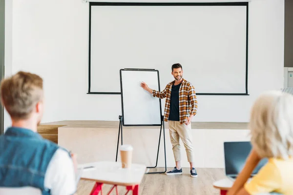 Bello giovane insegnante fare presentazione per gruppo di studenti al college — Foto stock