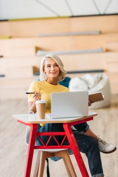 Smiling student girl sitting at lecture room with laptop — Stock Photo