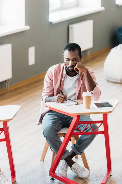 Gelangweilte afrikanisch-amerikanische Studentin sitzt während des Unterrichts am Schreibtisch — Stockfoto