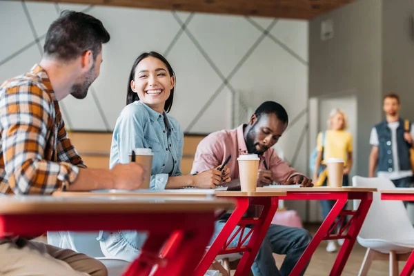 Felici giovani studenti che chattano in classe del college — Foto stock