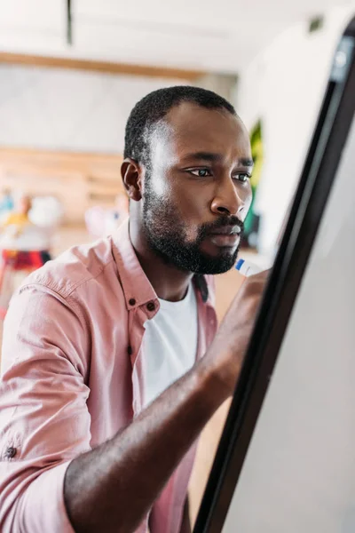 Concentrato giovane afroamericano uomo scrivere sulla lavagna bianca — Foto stock