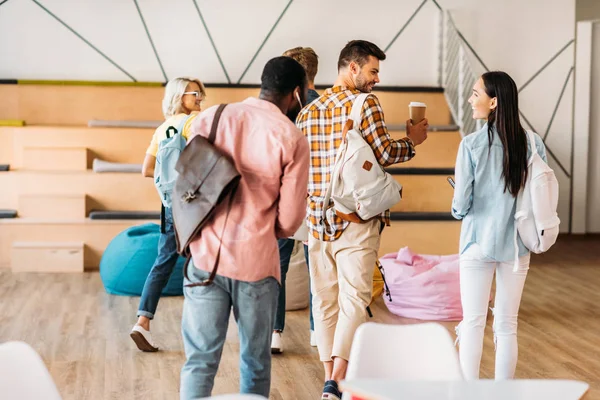 Vista trasera del grupo de jóvenes estudiantes caminando en la universidad - foto de stock