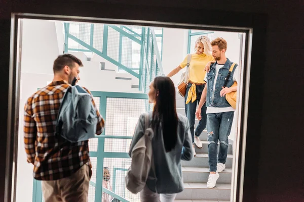 Jovens estudantes felizes andando em escadas na faculdade — Fotografia de Stock