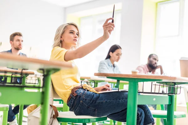 Estudiantes jóvenes concentrados sentados en el aula durante la lección - foto de stock