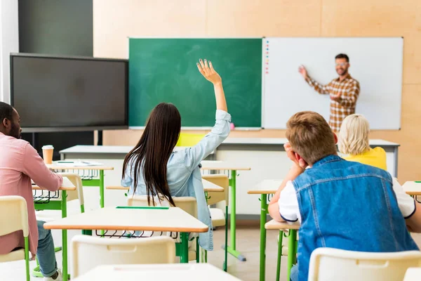 Rear view of young students listening to teachers lecture at college — Stock Photo