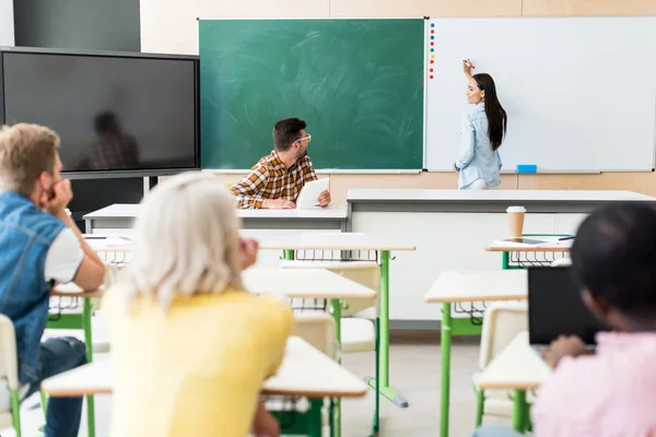Visão traseira de jovens estudantes sentados em sala de aula durante a aula — Fotografia de Stock