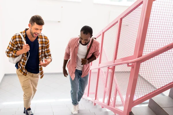 Young students walking upstairs at college corridor — Stock Photo