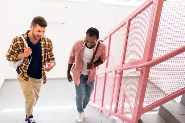 Jovens estudantes andando no andar de cima no corredor da faculdade — Fotografia de Stock