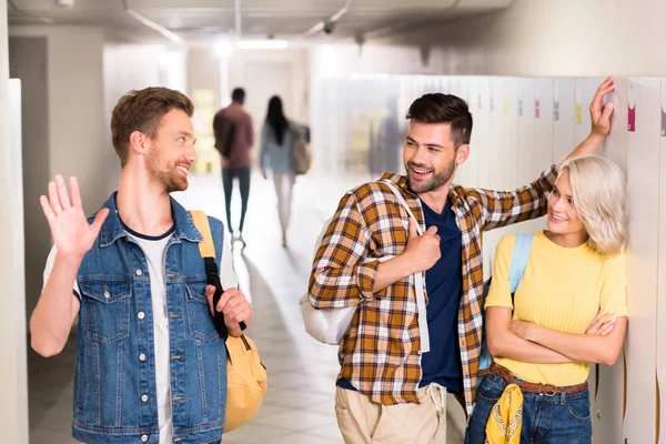Felici giovani studenti che si salutano nel corridoio del college — Foto stock