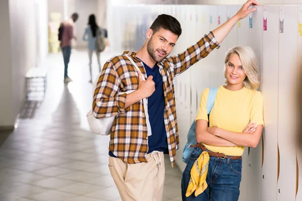 Giovani studenti coppia appoggiata su armadietti nel corridoio del college — Foto stock