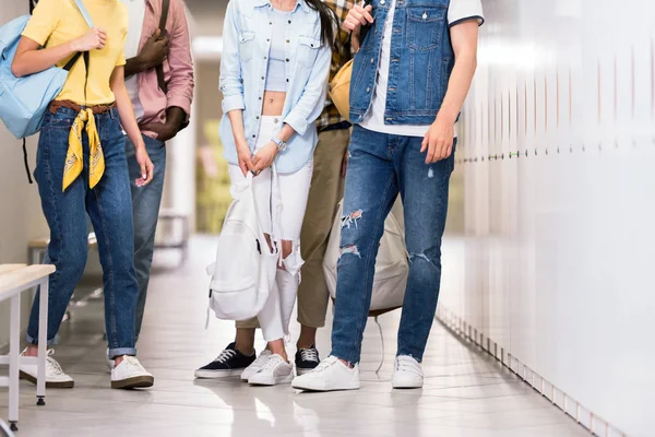 Tiro recortado de jovens estudantes elegantes em pé juntos no corredor da faculdade — Fotografia de Stock