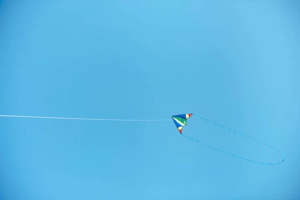 Pipa colorida voando alto no céu azul claro — Fotografia de Stock