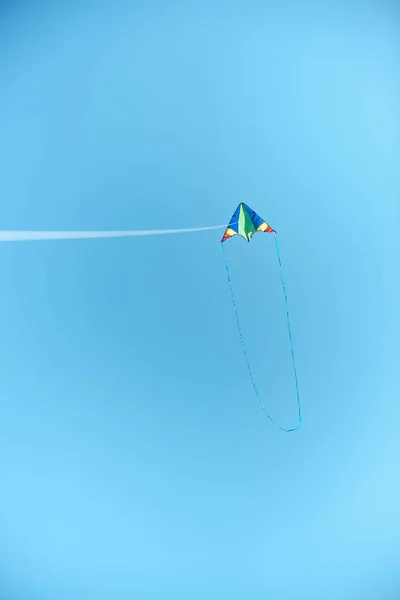 Pipa colorida voando alto no céu azul claro — Fotografia de Stock