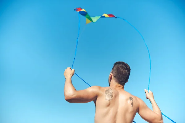 Back view of man with colorful kite against clear blue sky — Stock Photo